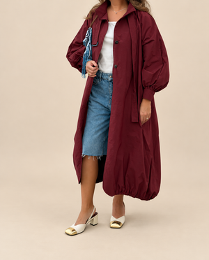 Burgundy balloon jacket on beige backdrop